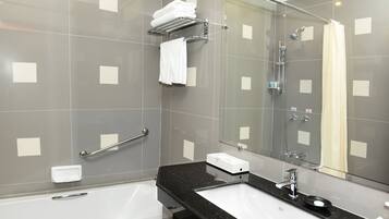 A modern bathroom with a bathtub, a sink, a mirror, and a shower area.