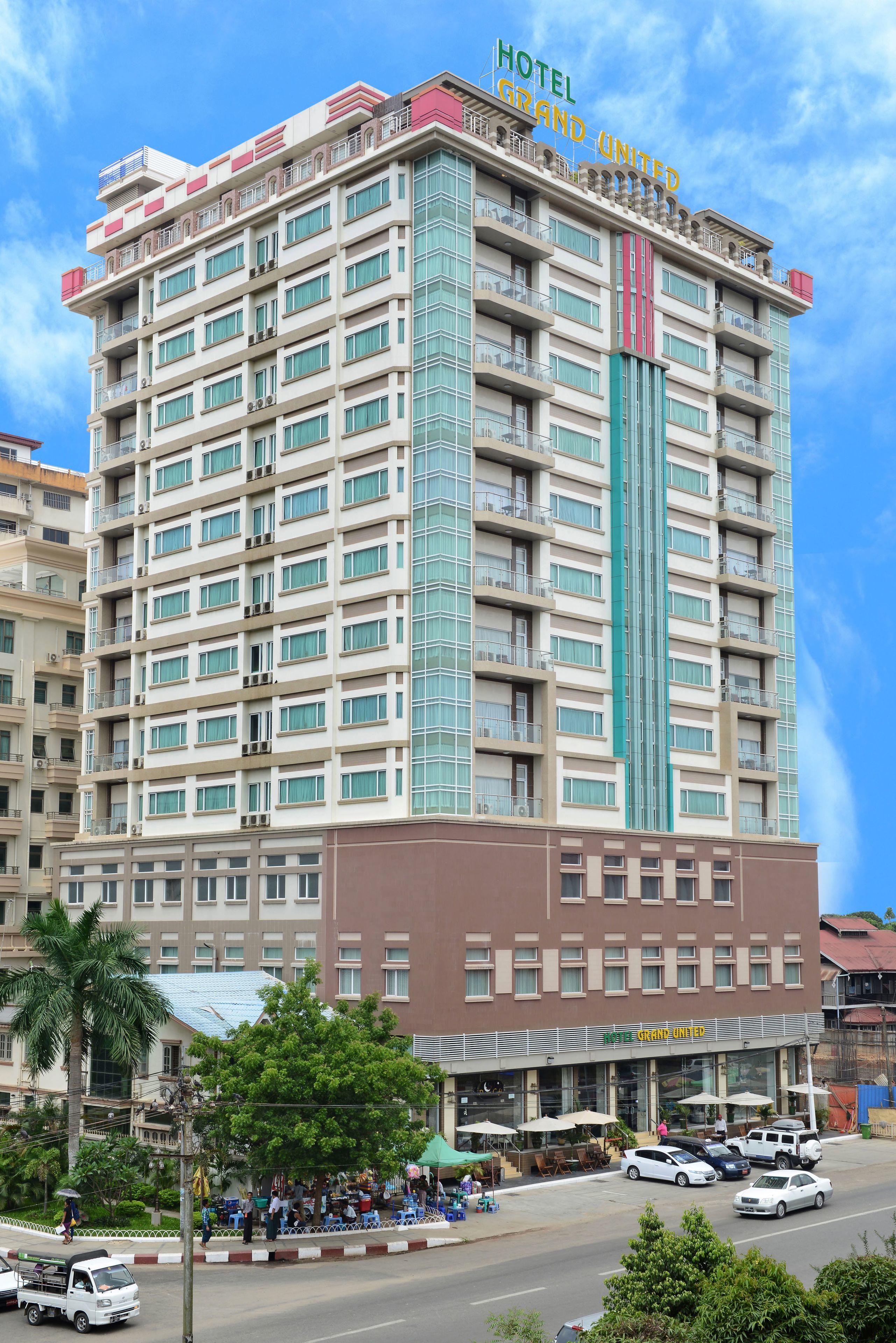 Un hôtel à plusieurs étages doté de balcons, d’un élément vertical central et d’un restaurant situé au rez-de-chaussée.