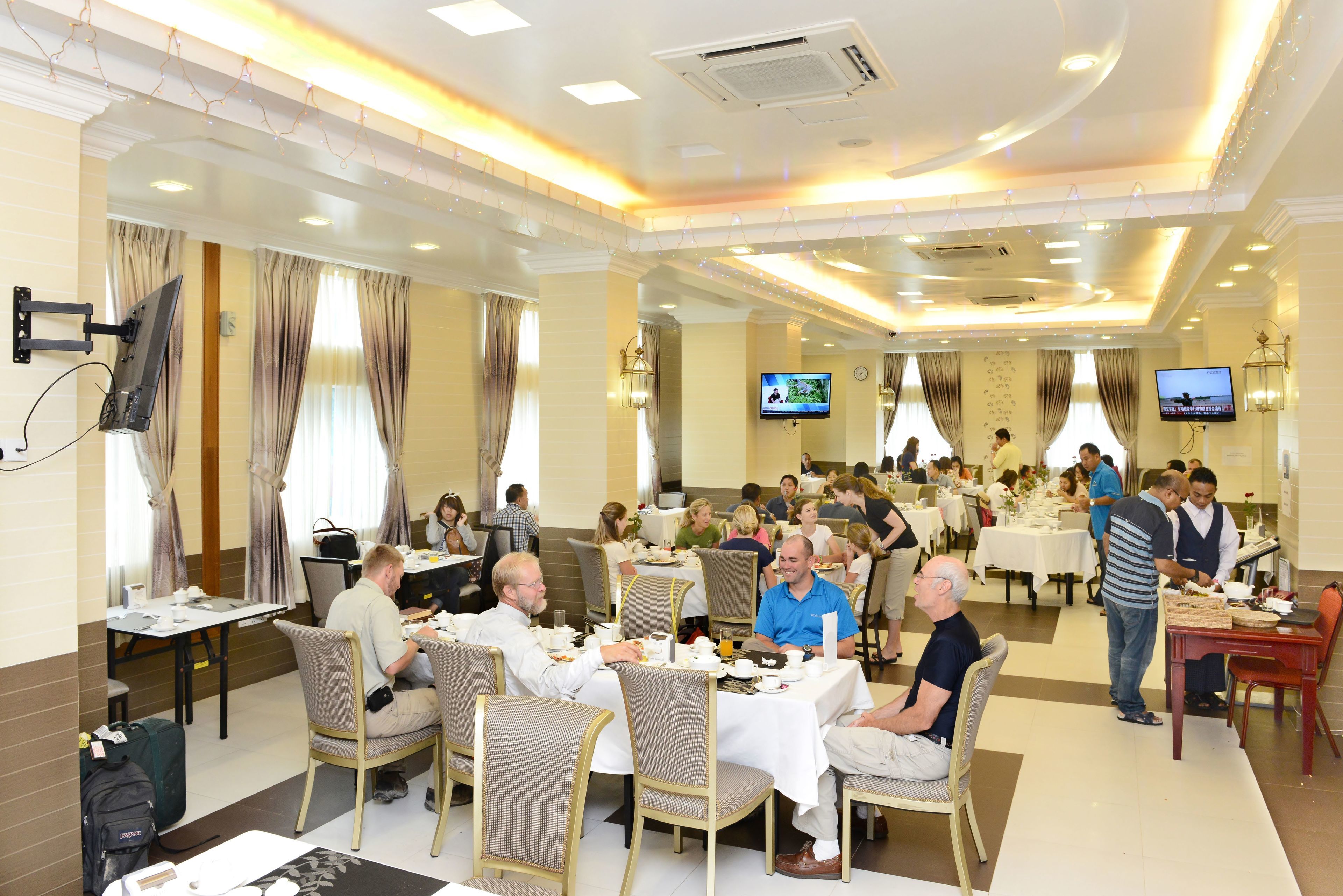 Zona pranzo con tavoli e sedie, una televisione a muro e un'area buffet.