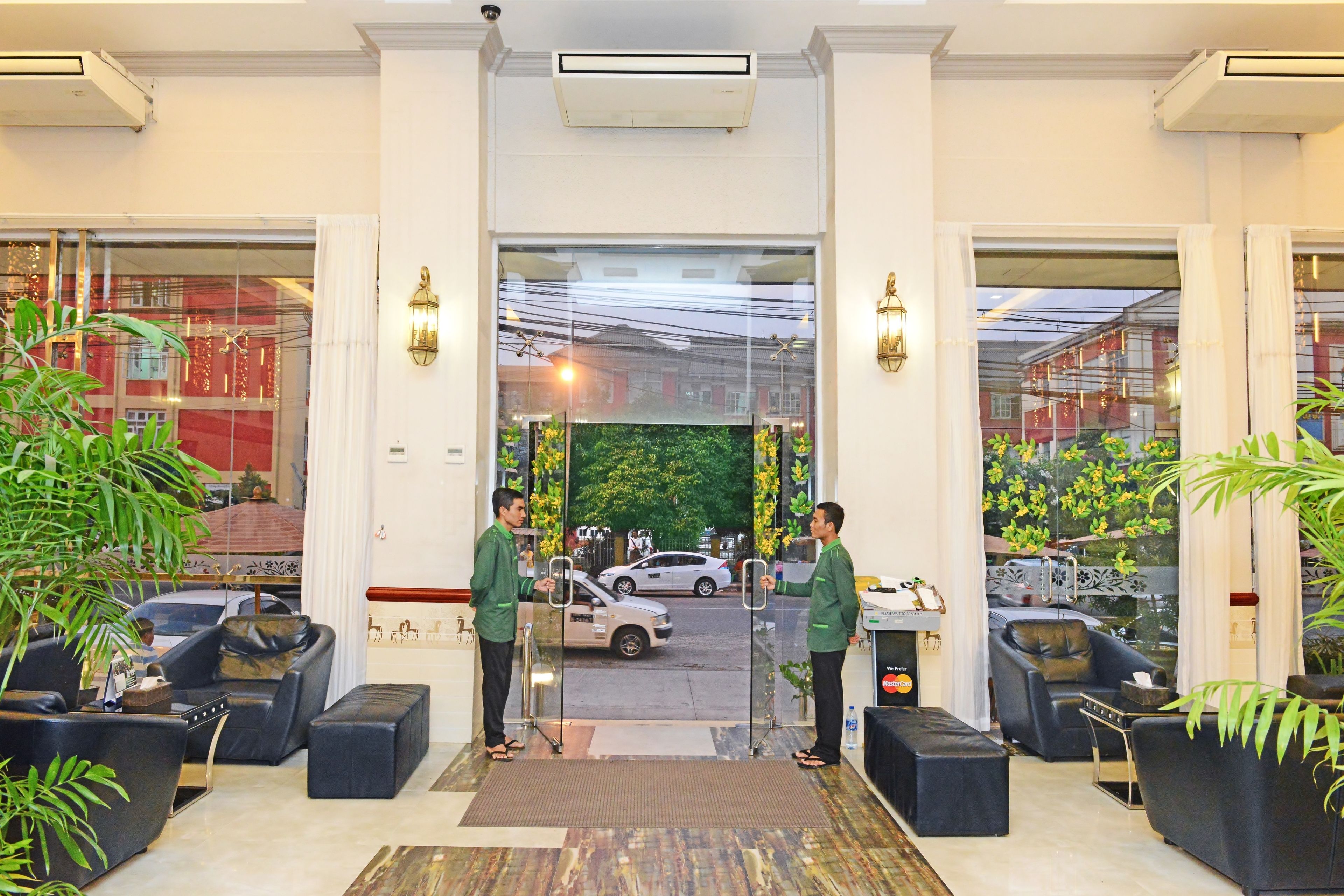 Un vestíbulo de hotel con zonas de estar, un mostrador de recepción y vistas a la calle.