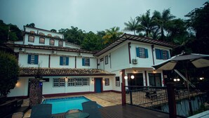 A two-story building with a swimming pool, outdoor seating, and a staircase leading to an upper level. - Hotel Solar das Lajes (Ouro Preto)