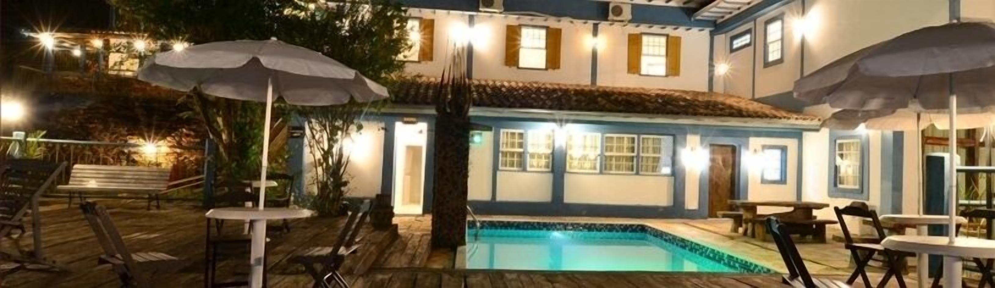 Zona junto a la piscina con sombrillas, piscina y mobiliario de exterior.