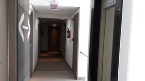 A corridor with an elevator on the right, a sign indicating 'SAIDA' overhead, and a fire extinguisher on the wall. - Hotel Valerim Itajaí (Itajai)