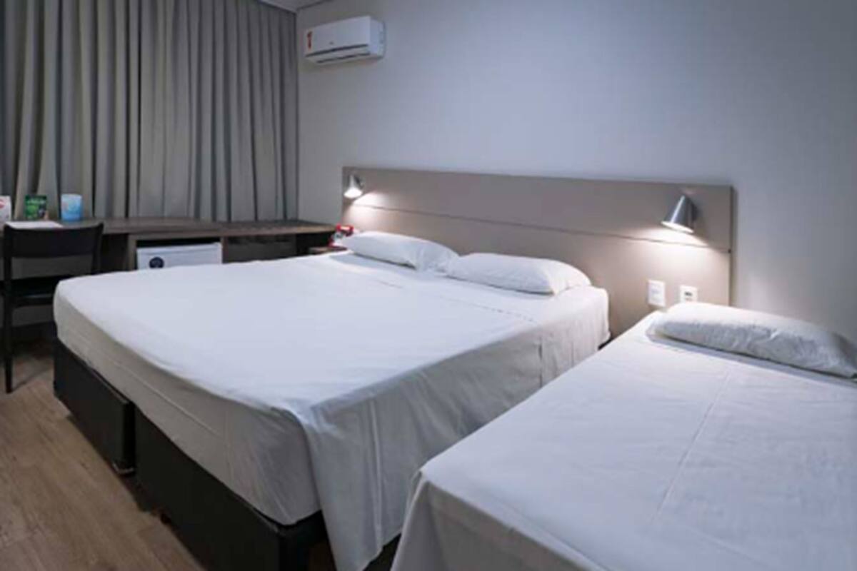 A hotel room with two beds, a desk, and a chair.