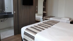 A hotel room with two beds, a TV mounted on the wall, a mirror, and a wardrobe. - Hotel Valerim Itajaí (Itajai)