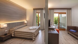 A hotel room with a bed, bedside table, TV, and a balcony with a table and chairs. - Ethra Reserve - Valentino 4* (Castellaneta Marina)