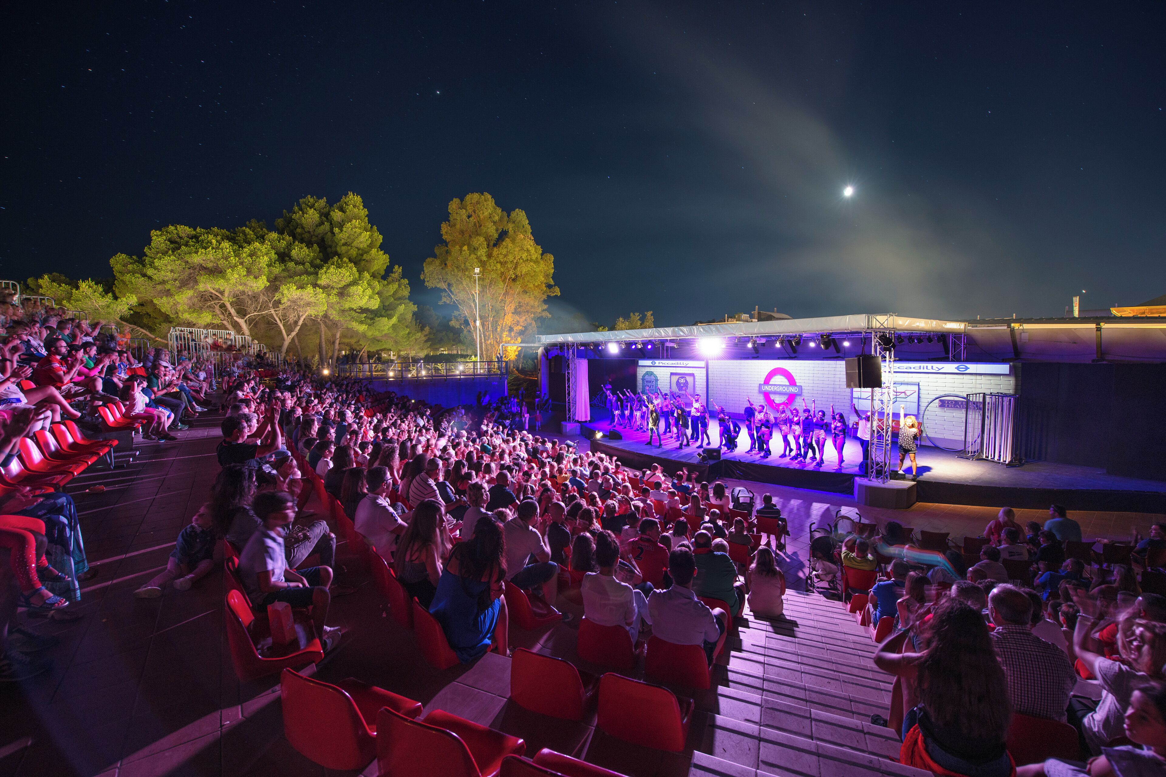 An outdoor amphitheater with tiered seating and a stage for performances.