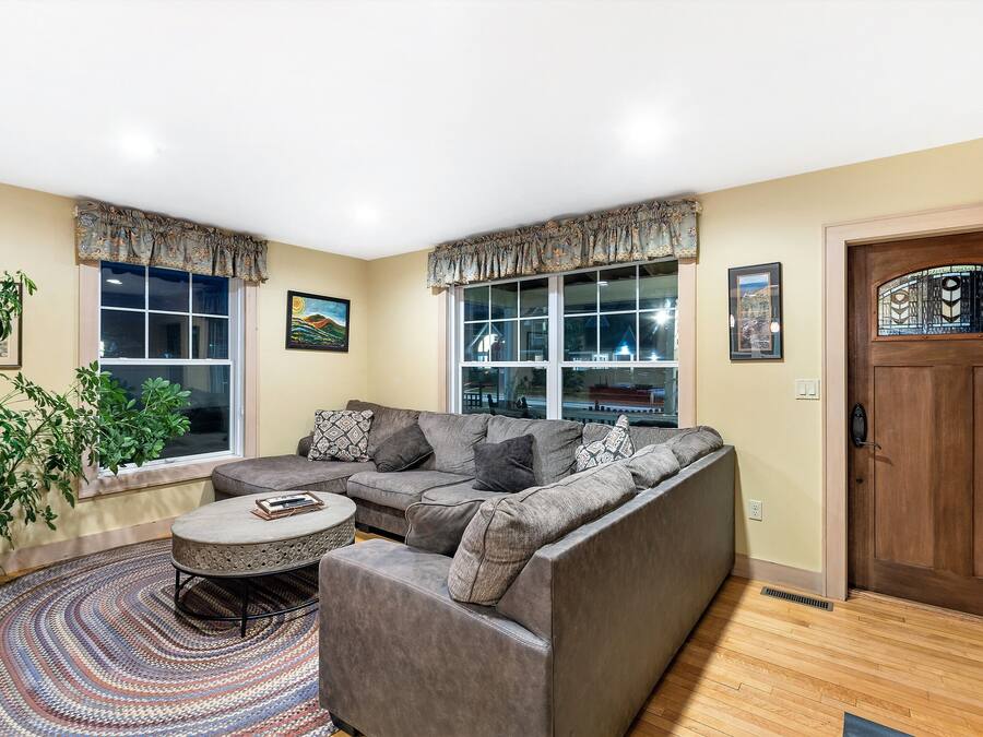 A living room with a sectional sofa, a round coffee table, and a large window with a view.