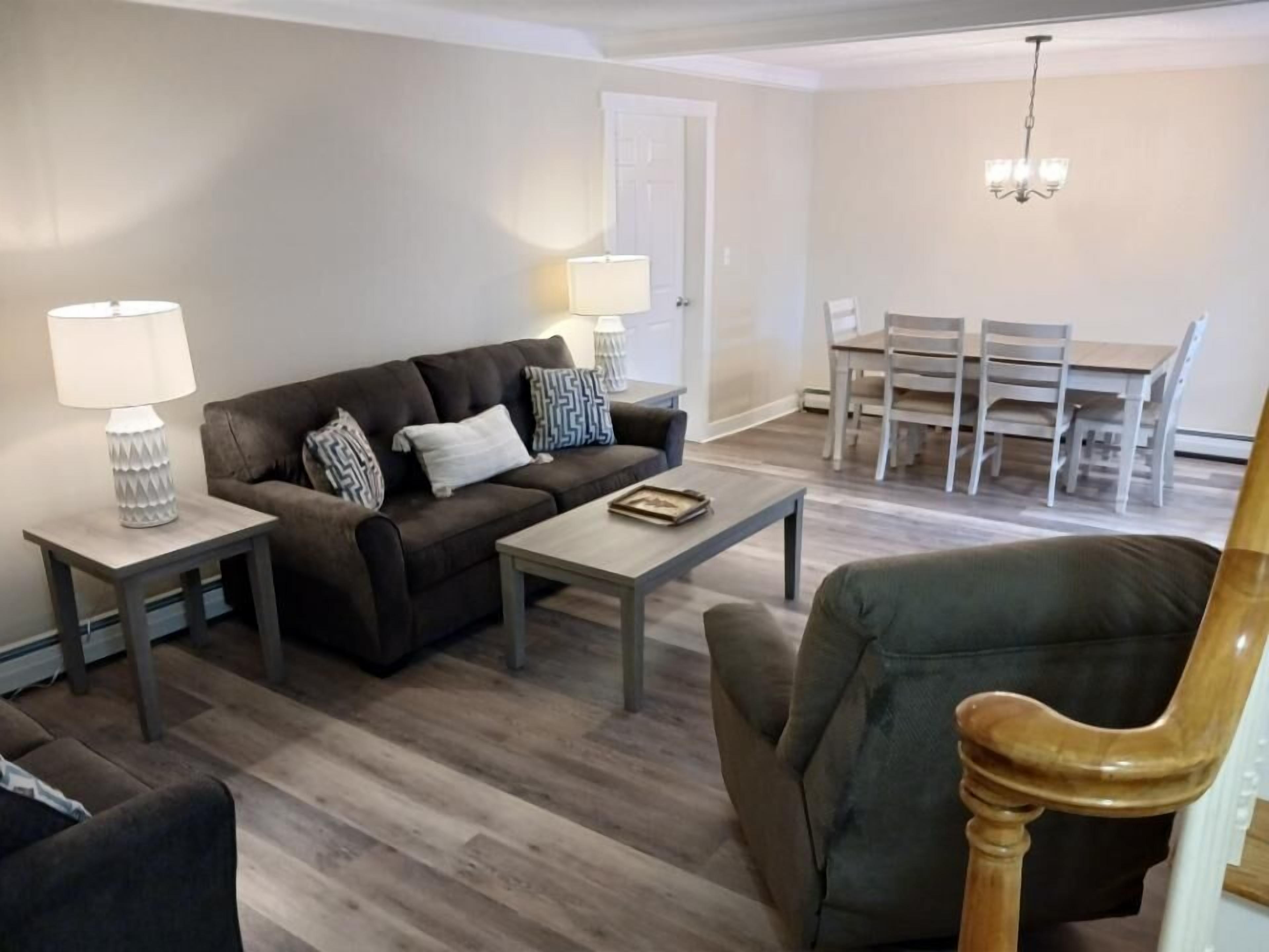 Una sala de estar con sofá, mesa de centro y comedor con mesa y sillas.