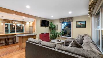 A modern living room with a sofa, a small coffee table, and a kitchen area with wooden flooring and a bar counter.
