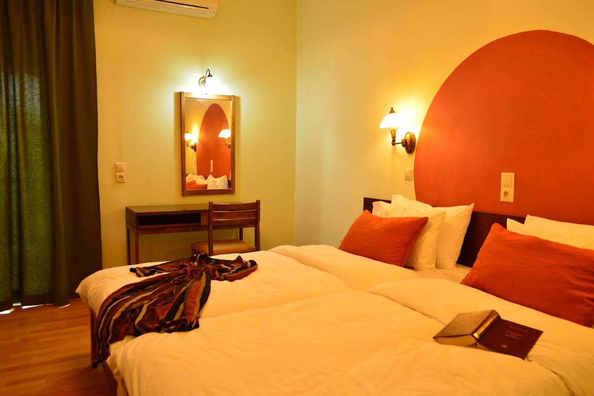 A hotel room with a bed, a desk, a chair, and a large mirror.