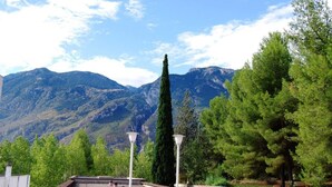 Una terraza en la azotea con vistas a montañas, árboles y dos farolas.