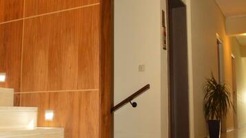 A modern interior with a wooden staircase, a potted plant, and a hallway leading to another room.