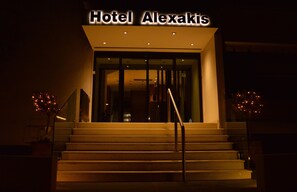 Hotel Alexakis with a modern entrance, glass doors, and a staircase leading up to the entrance.