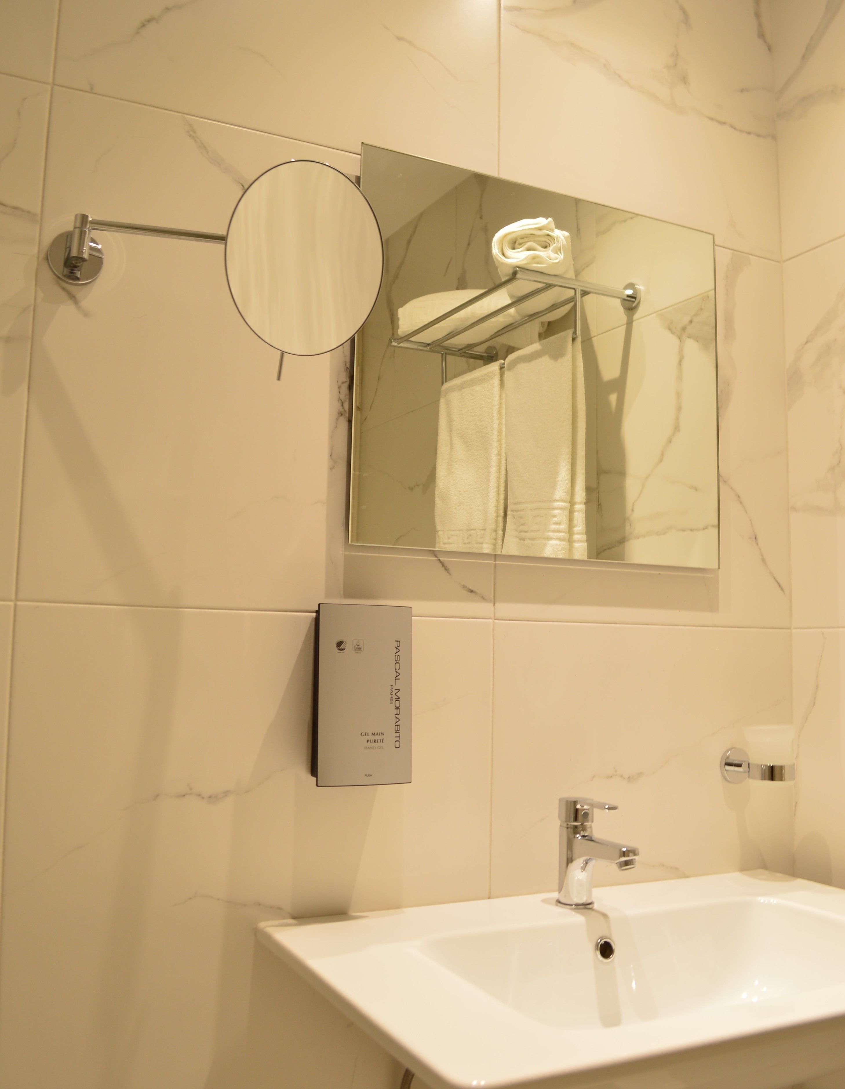 Ein Badezimmer mit einem weißen Waschbecken, einem Spiegel und einem Handtuchhalter.