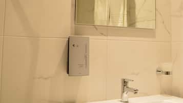 Ein Badezimmer mit einem weißen Waschbecken, einem Spiegel und einem Handtuchhalter.