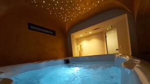 Un jacuzzi con un techo de luces pequeñas, un cartel en la pared y una puerta al fondo.