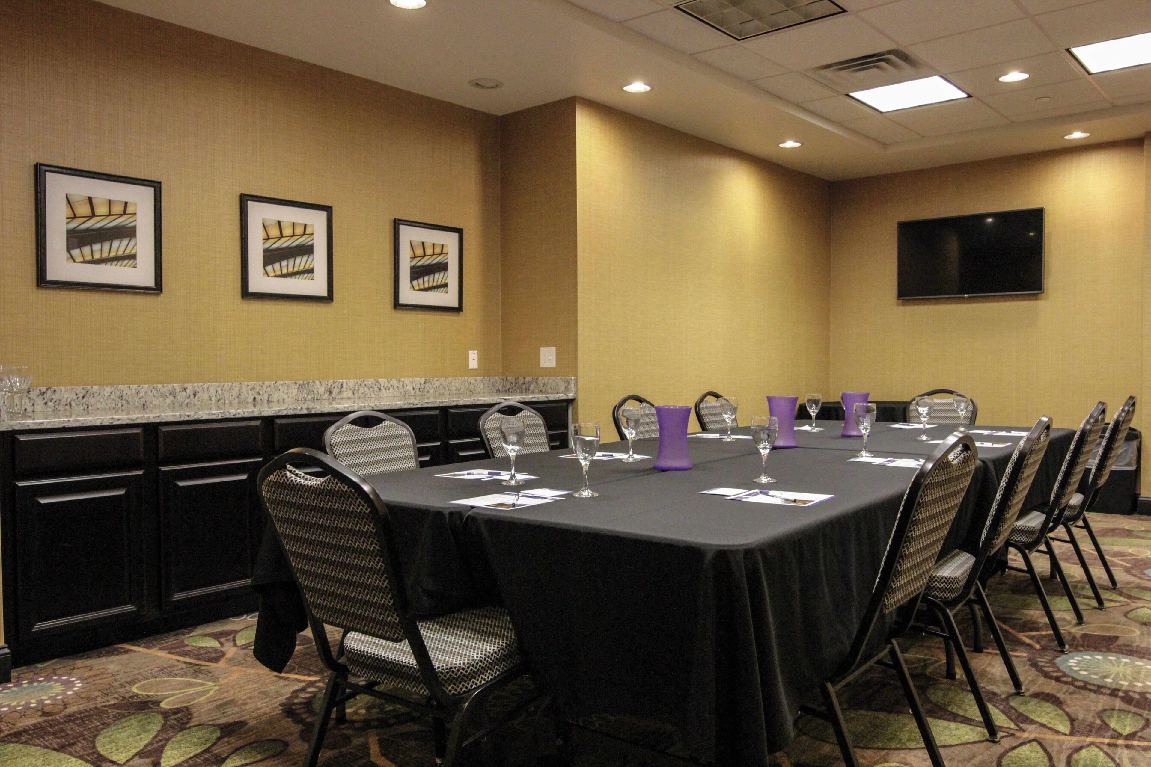 A conference room with a long table, chairs, and framed pictures on the wall.