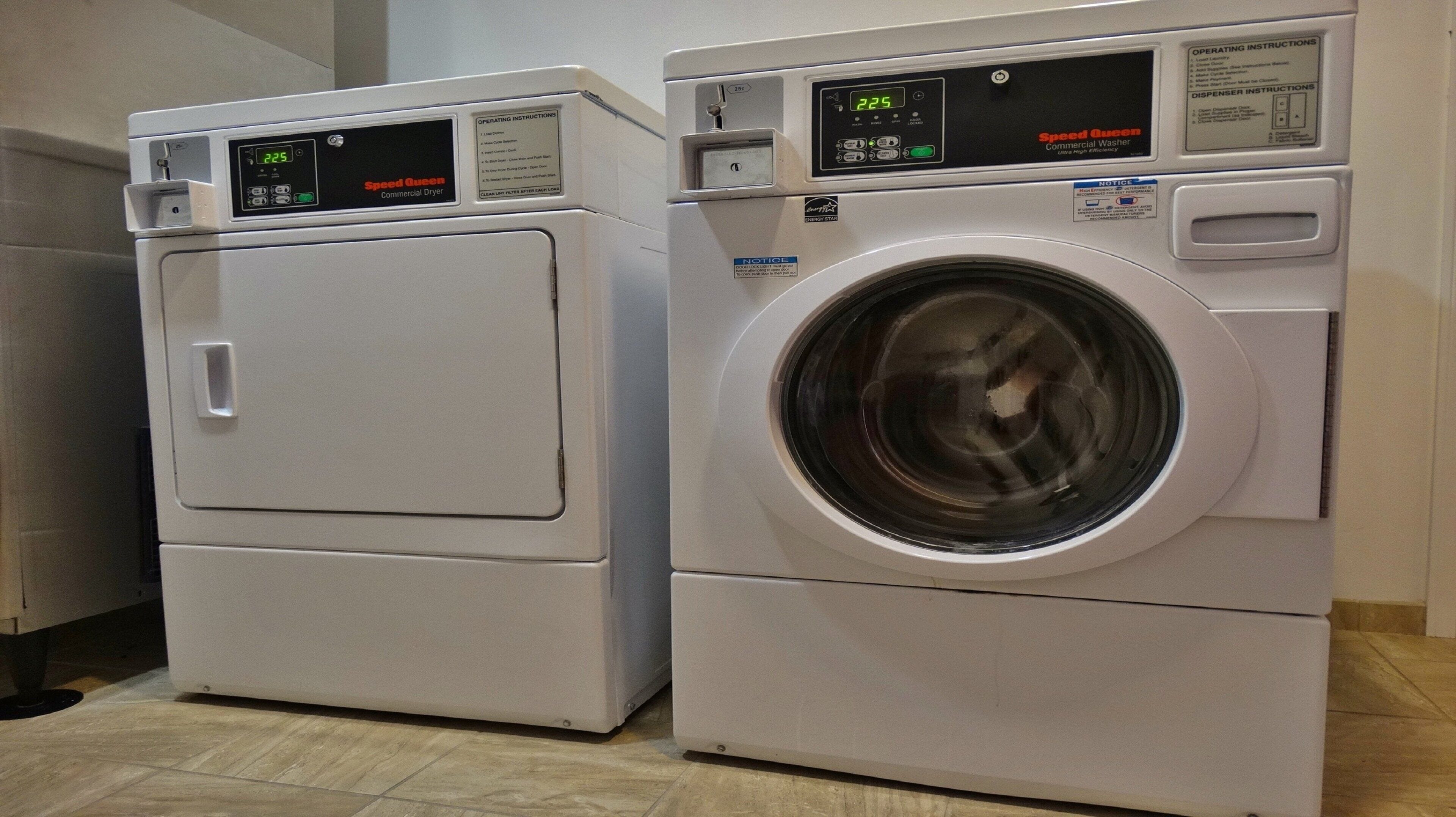 Two white commercial dryers, one with a digital display and the other with a control panel.