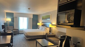 Una habitación de hotel con cama, escritorio, sofá, cafetera y microondas.
