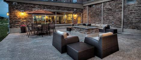 An outdoor patio area with stone walls, a fire pit, and outdoor furniture.