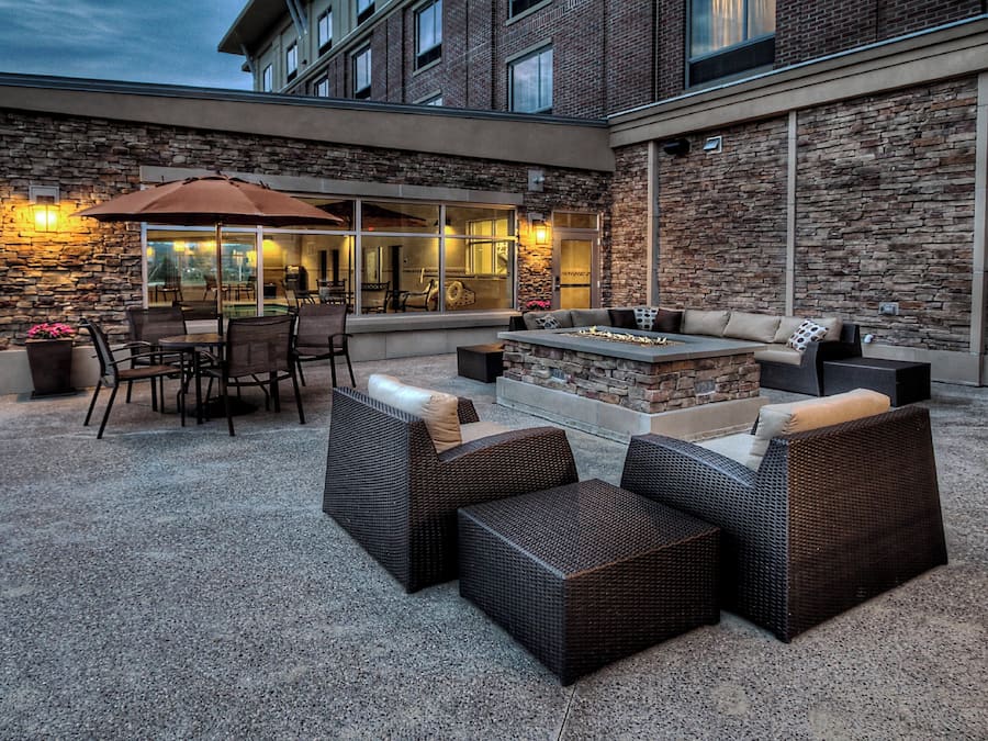 Un espace extérieur aménagé en terrasse, avec des murs en pierre, un foyer et du mobilier d’extérieur.