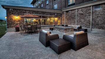 Un área de patio al aire libre con muros de piedra, un brasero y mobiliario exterior.