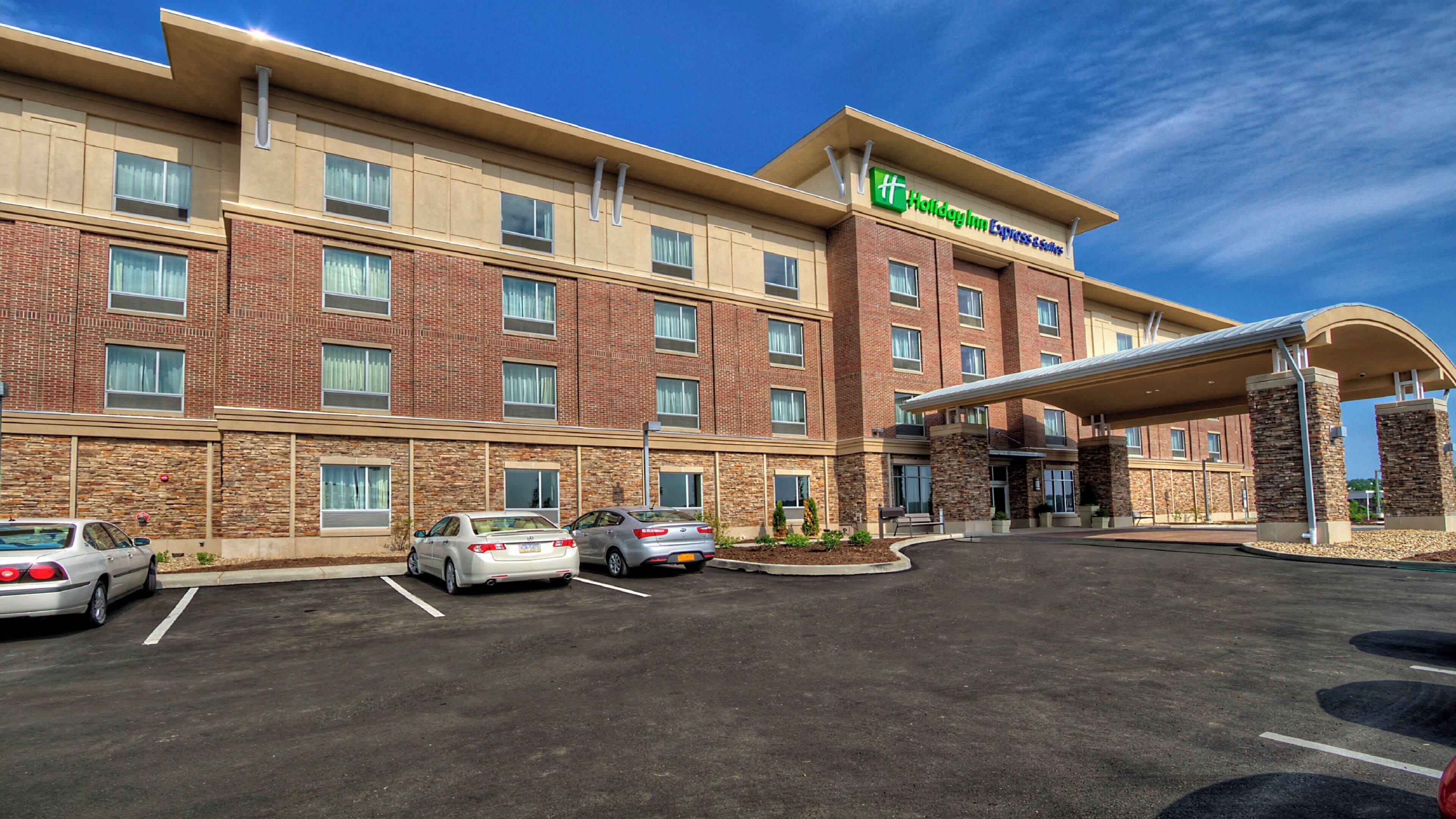 A Holiday Inn Express building with a brick facade, a covered entrance, and a parking lot with several cars.