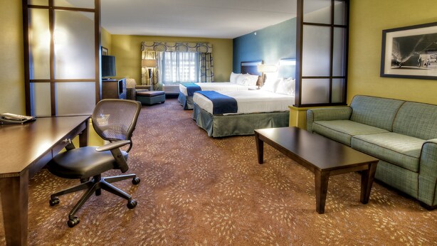 Een hotelkamer met een bed, een bureau, een stoel, een bank en een vloerbedekking.