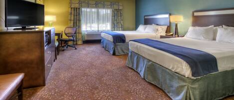 A hotel room with two beds, a desk with a TV, a chair, and a window with curtains.
