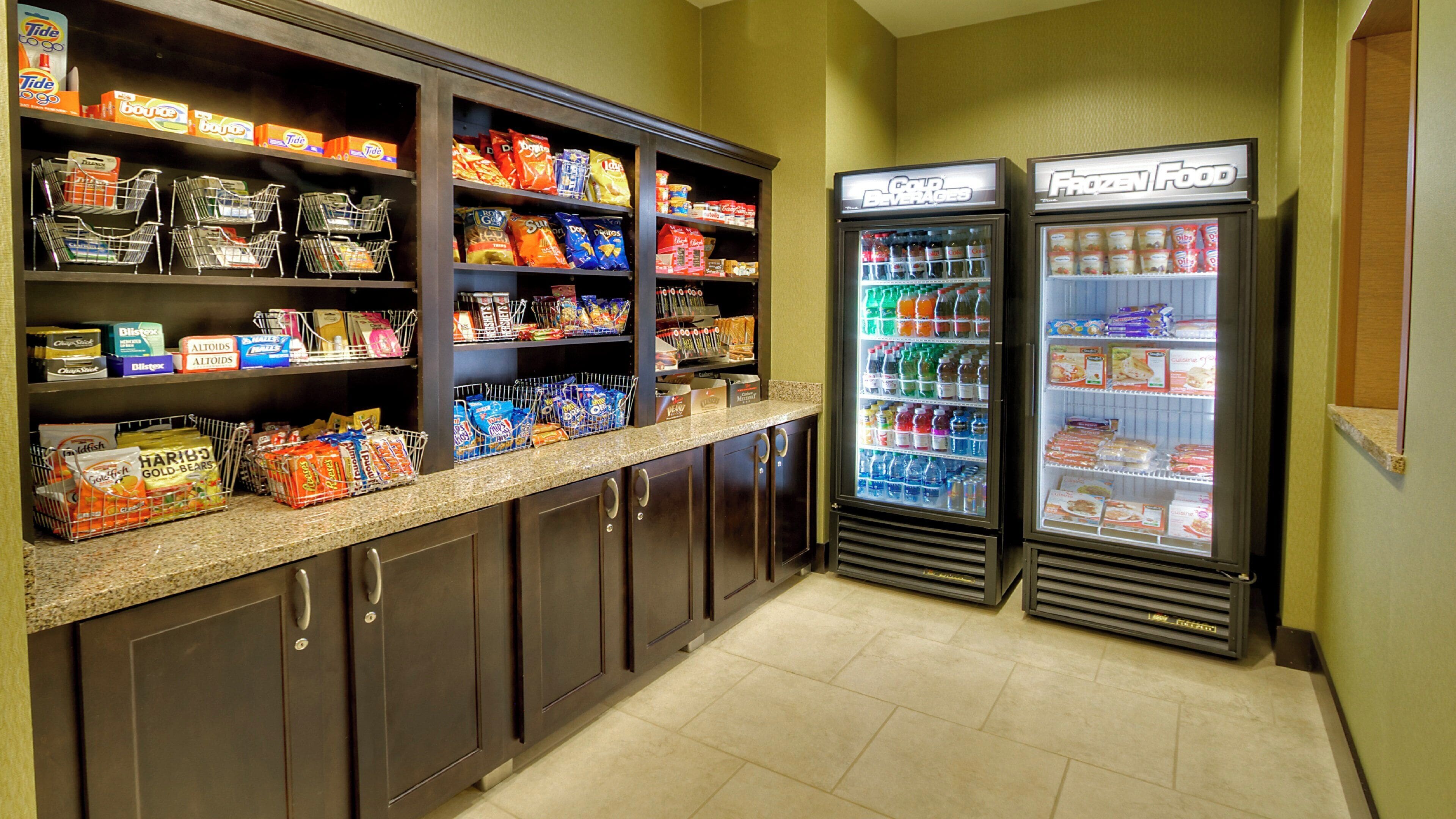 A self-service food area with refrigerated beverage dispensers and shelves stocked with snacks and beverages.