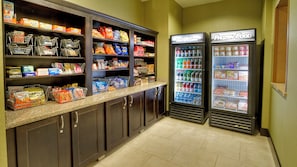 A self-service food area with refrigerated beverage dispensers and shelves stocked with snacks and beverages.