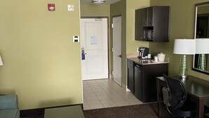 Een hotelkamer met een kitchenette, een klein eethoekje en een deur naar een andere kamer.