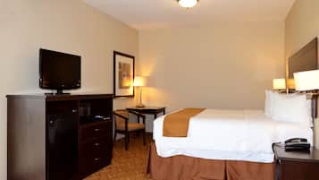 A hotel room with a bed, a desk, a chair, a television, and a telephone.