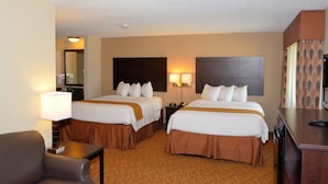 A hotel room with two beds, a desk, a chair, a television, and a bathroom visible in the background.