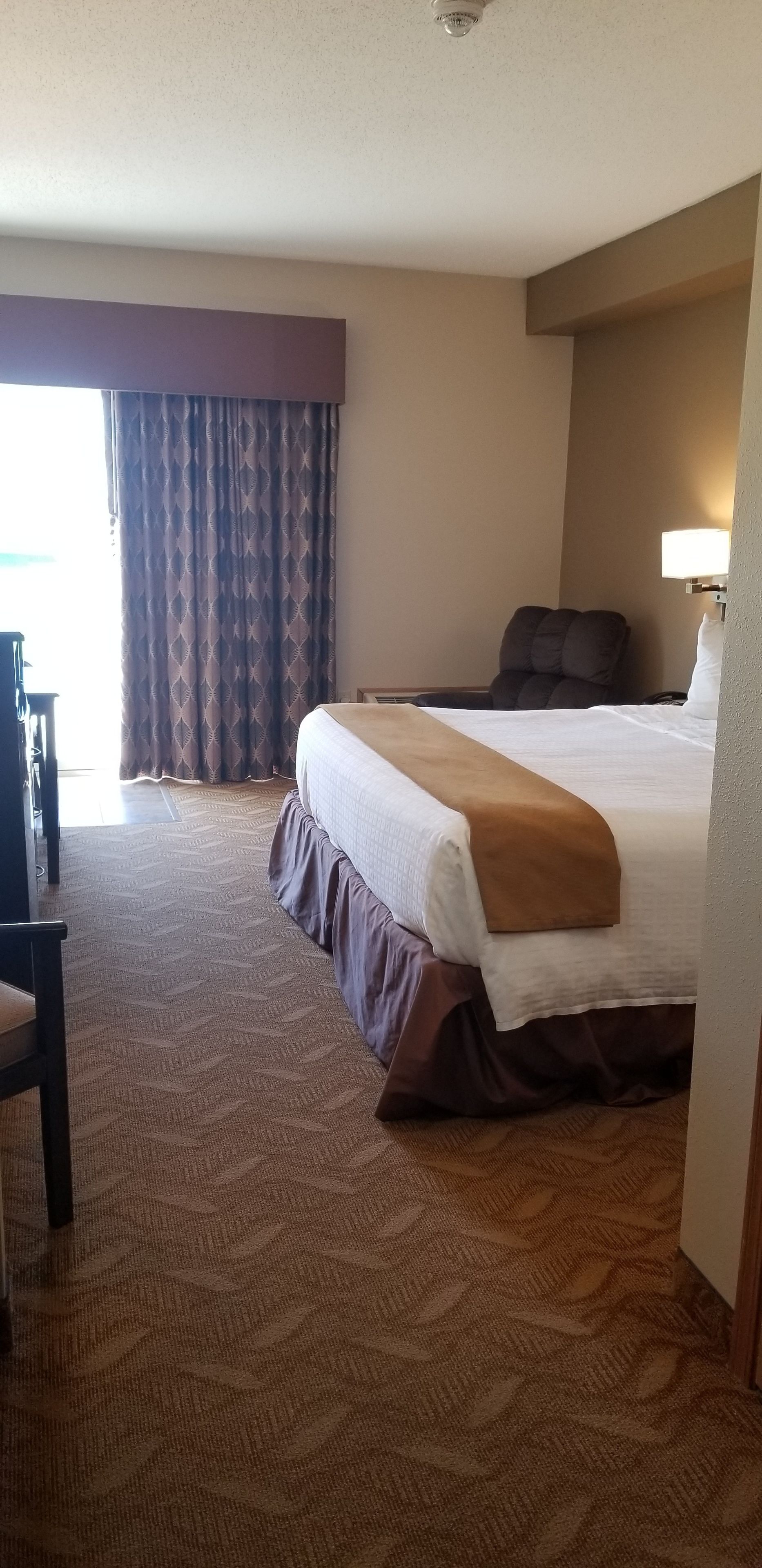 Una habitación de hotel con una cama grande, un escritorio y una silla.