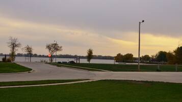 A parking lot with a stop sign, a street lamp, and a body of water in the background.