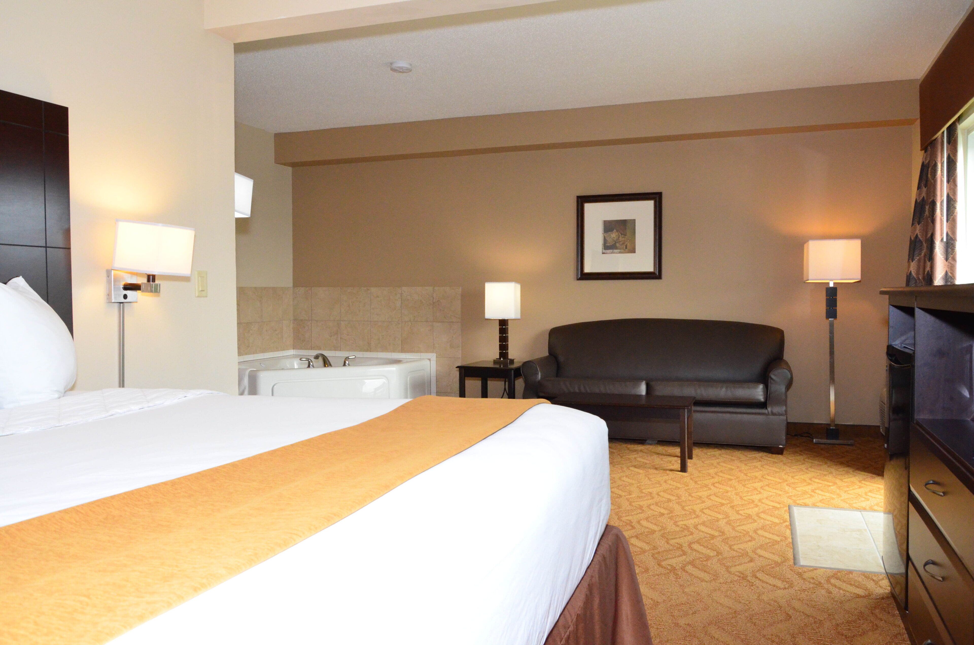 Ein Hotelzimmer mit einem großen Bett, einer Couch, einer Badewanne und einem Fernseher.