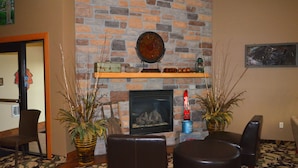 A cozy living room with a stone fireplace, leather seating, and decorative plants.
