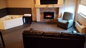 Un salon moderne avec une cheminée, un grand téléviseur à écran plat, un canapé et une baignoire.