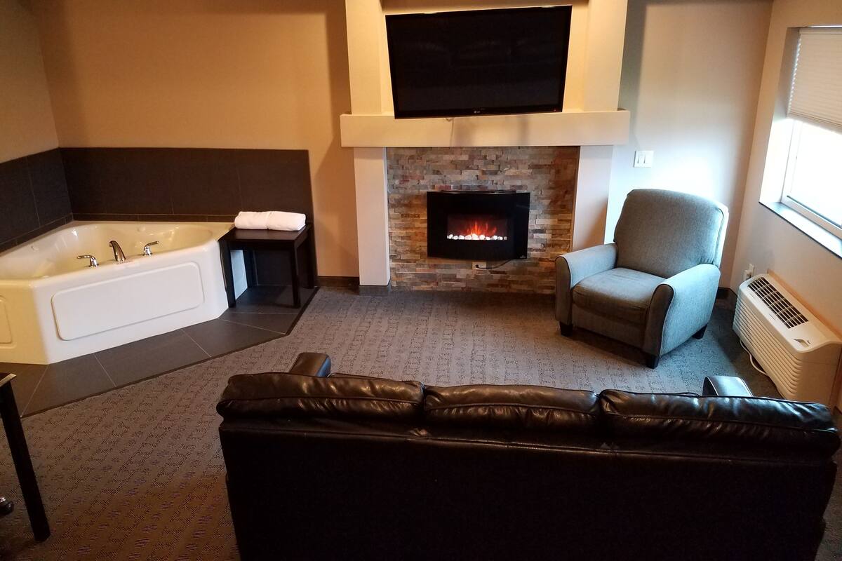 Una sala de estar moderna con chimenea, un televisor de pantalla plana grande, un sofá y una bañera.