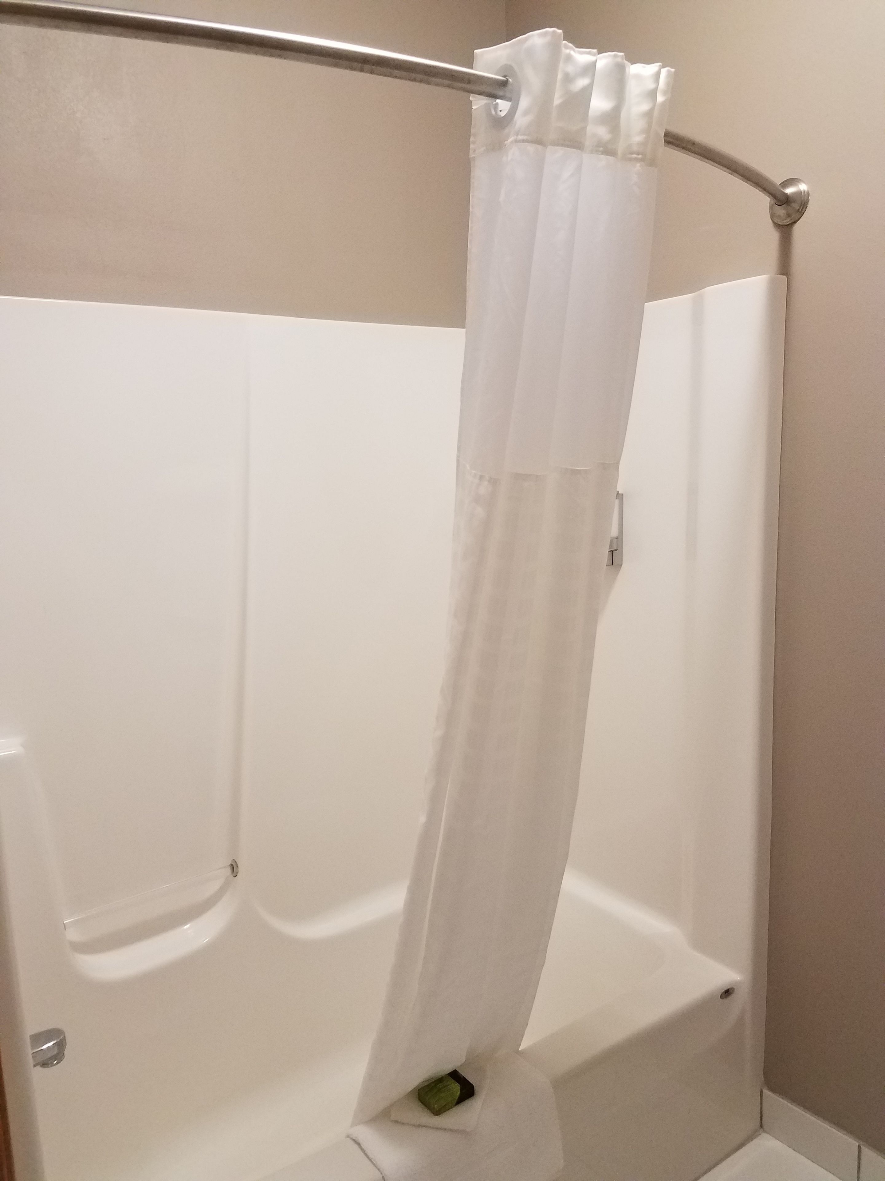 A white shower curtain in a bathroom with a bathtub.