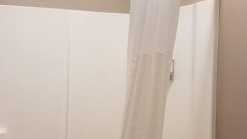 Cortina de ducha blanca en un baño con bañera.