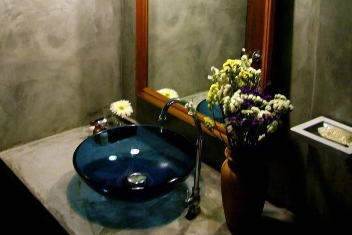 A bathroom with a blue sink, a mirror, and framed pictures on the wall.