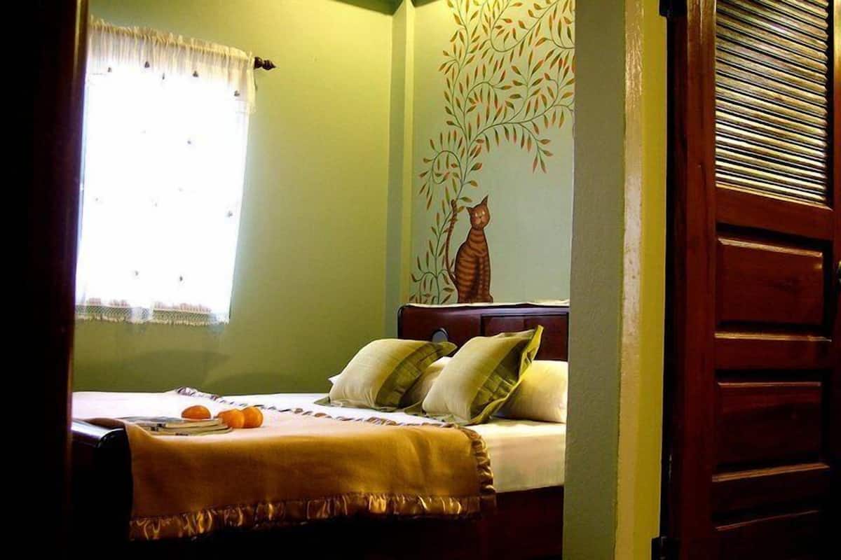 A bedroom with a bed, pillows, and a window with a curtain.
