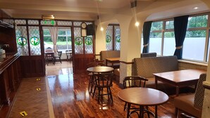 A restaurant interior with wooden flooring, round tables, and chairs. - Abbey Hotel (Ballyvourney)