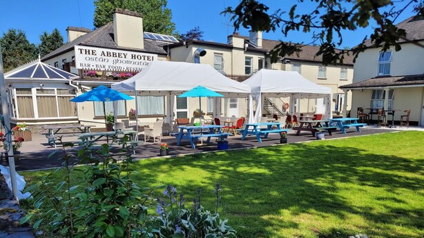 The Abbey Hotel with outdoor seating and a well-maintained lawn. - Abbey Hotel (Ballyvourney)