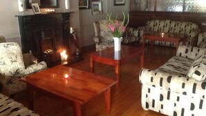 A living room with a fireplace, patterned sofas, and a coffee table. - Abbey Hotel (Ballyvourney)