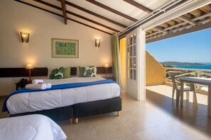 A hotel room with a bed, two bedside tables, a nightstand, a painting, and a balcony with a table and chairs. - Pousada e Spa Villa Mercedes by Latitud Hoteles (Búzios)