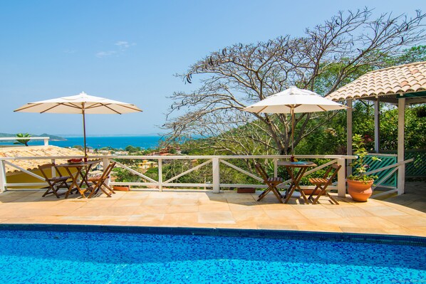 A poolside area with a view of the sea, outdoor furniture, and umbrellas. - Pousada e Spa Villa Mercedes by Latitud Hoteles (Búzios)